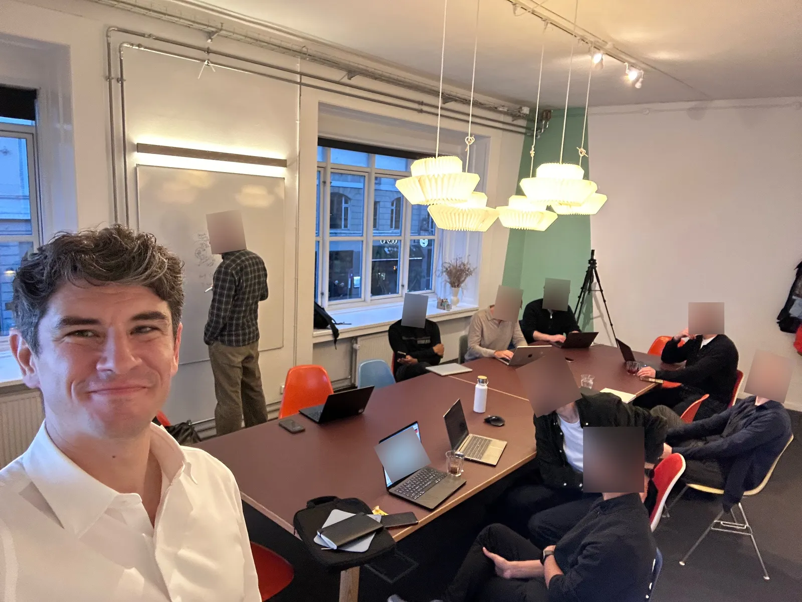 Hadrien taking a selfie at the workshop in Republikken: participants around a table with laptops, one at the whiteboard, faces blurred